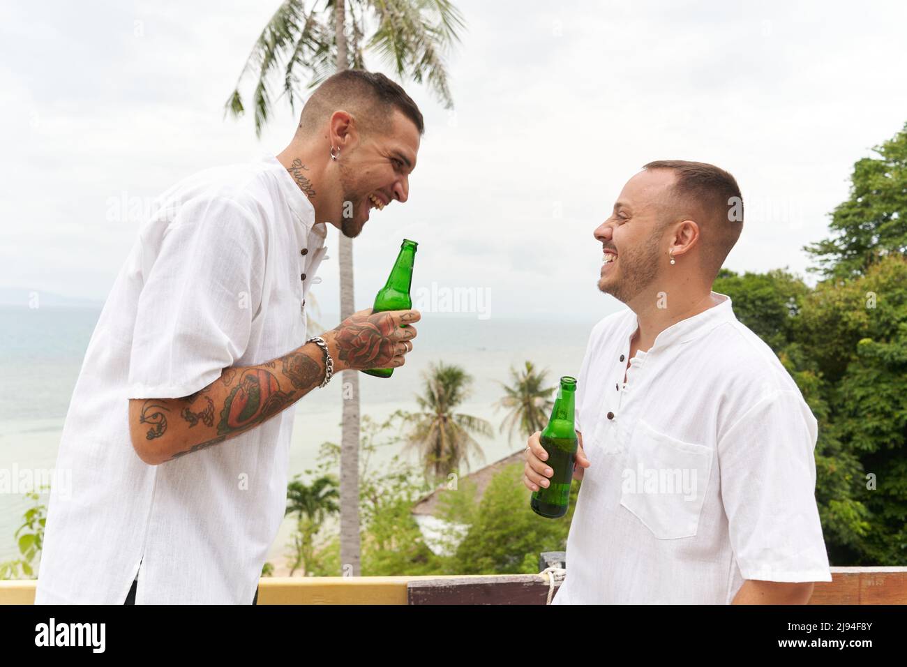 Coppia gay bere birra mentre ride e parlare all'aperto Foto Stock