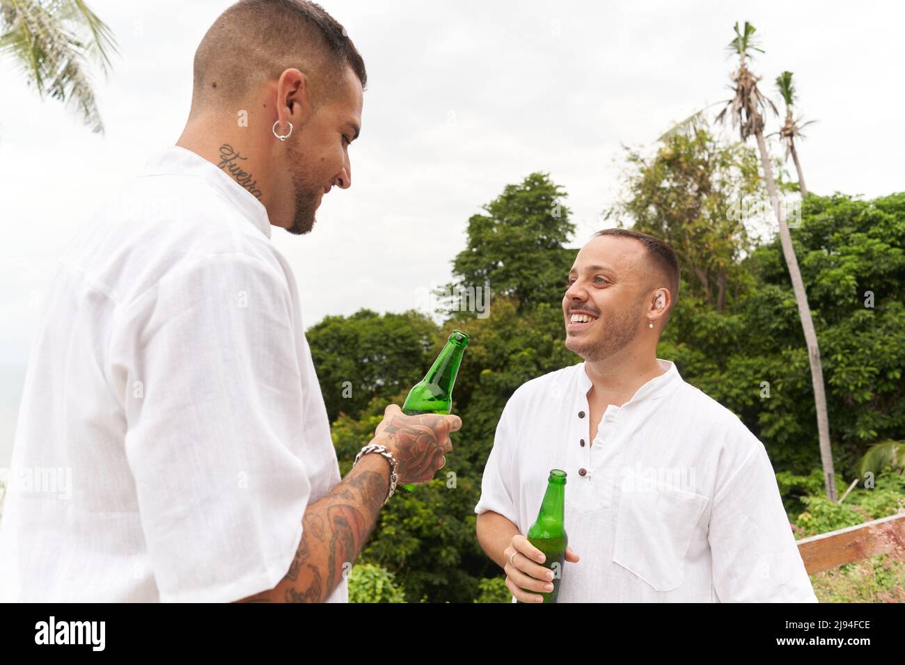 Sorridente coppia gay bere birra mentre si parla all'aperto Foto Stock