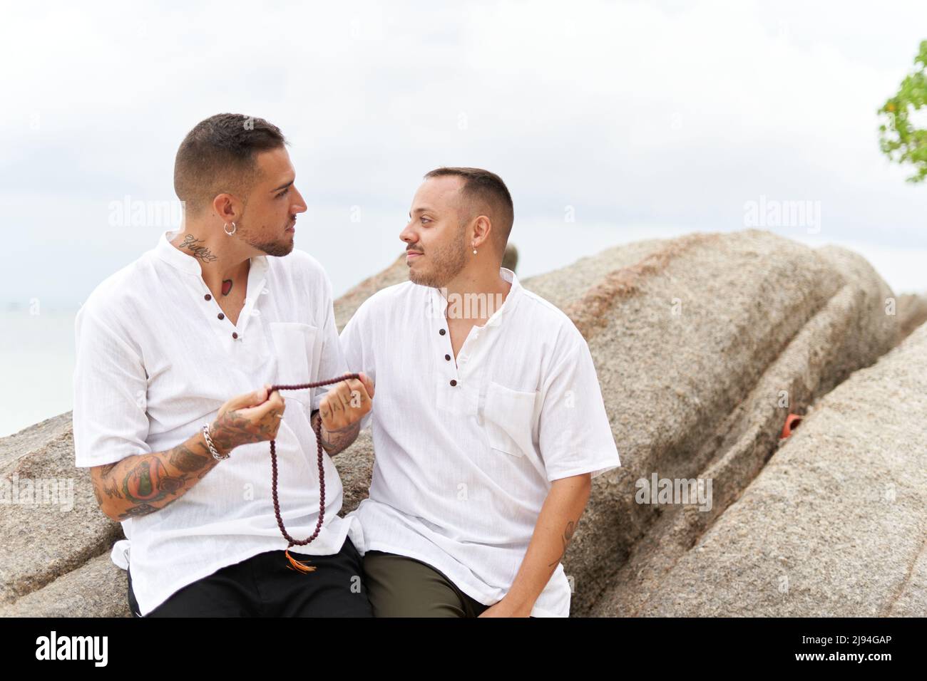 Coppia gay guardarsi teneramente con una collana nelle loro mani Foto Stock
