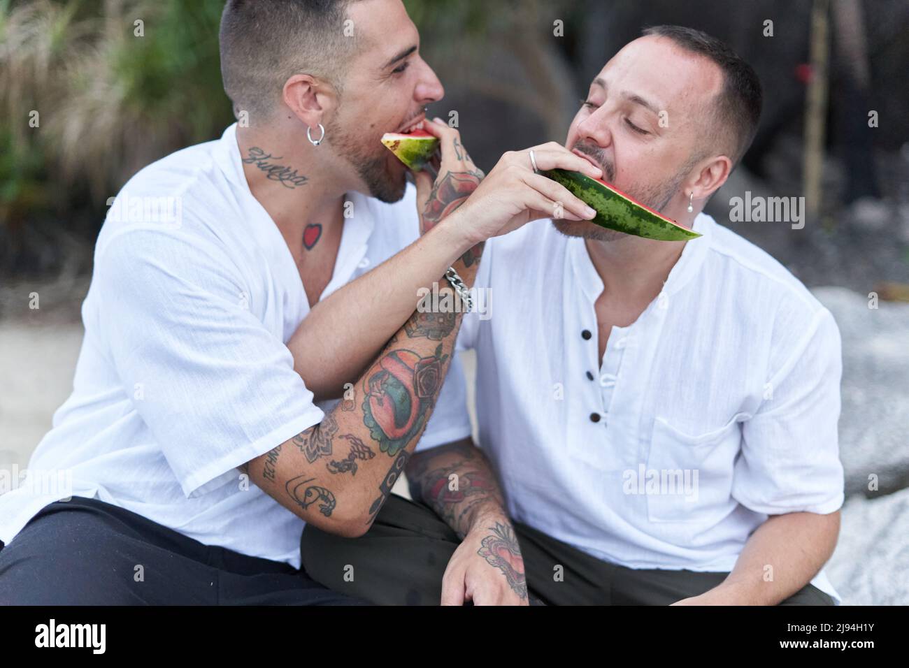 Coppia gay che si nutrono l'un l'altro con l'anguria all'aperto Foto Stock