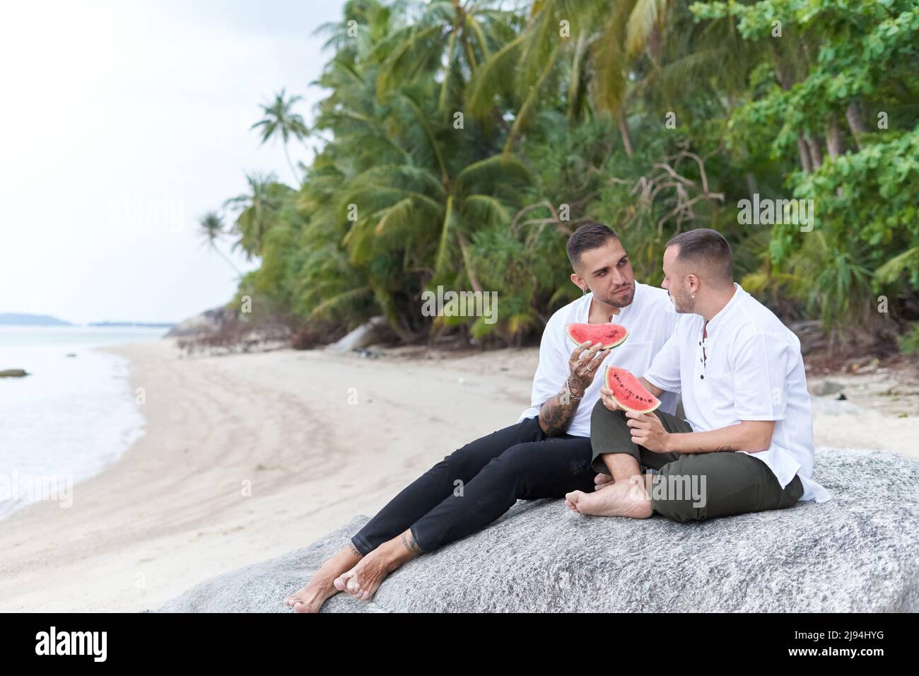 Foto con spazio di copia di una coppia gay che chiacchiera mentre mangiava l'anguria Foto Stock