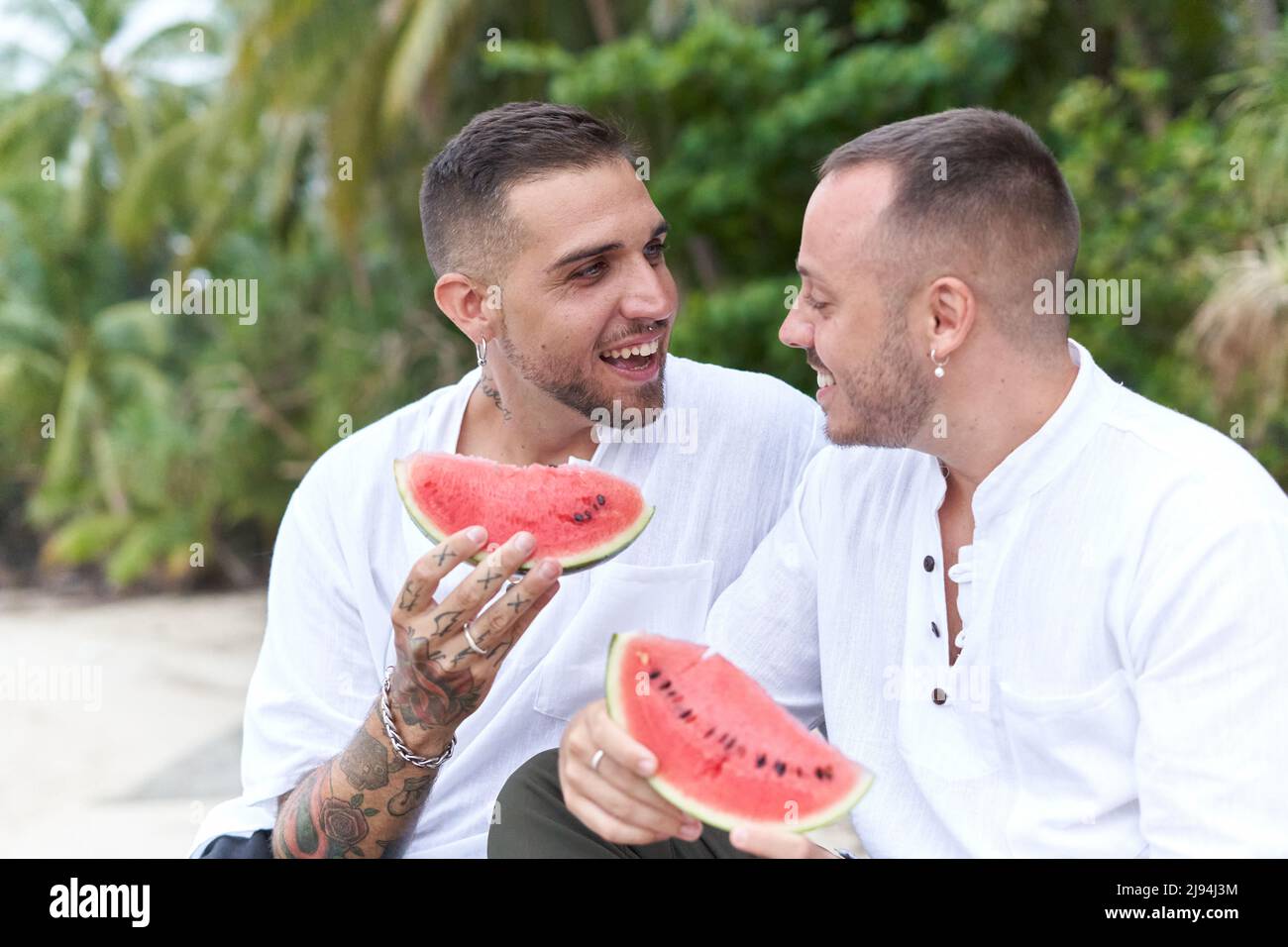 Coppia gay chiacchierando distratto mentre mangiava l'anguria Foto Stock