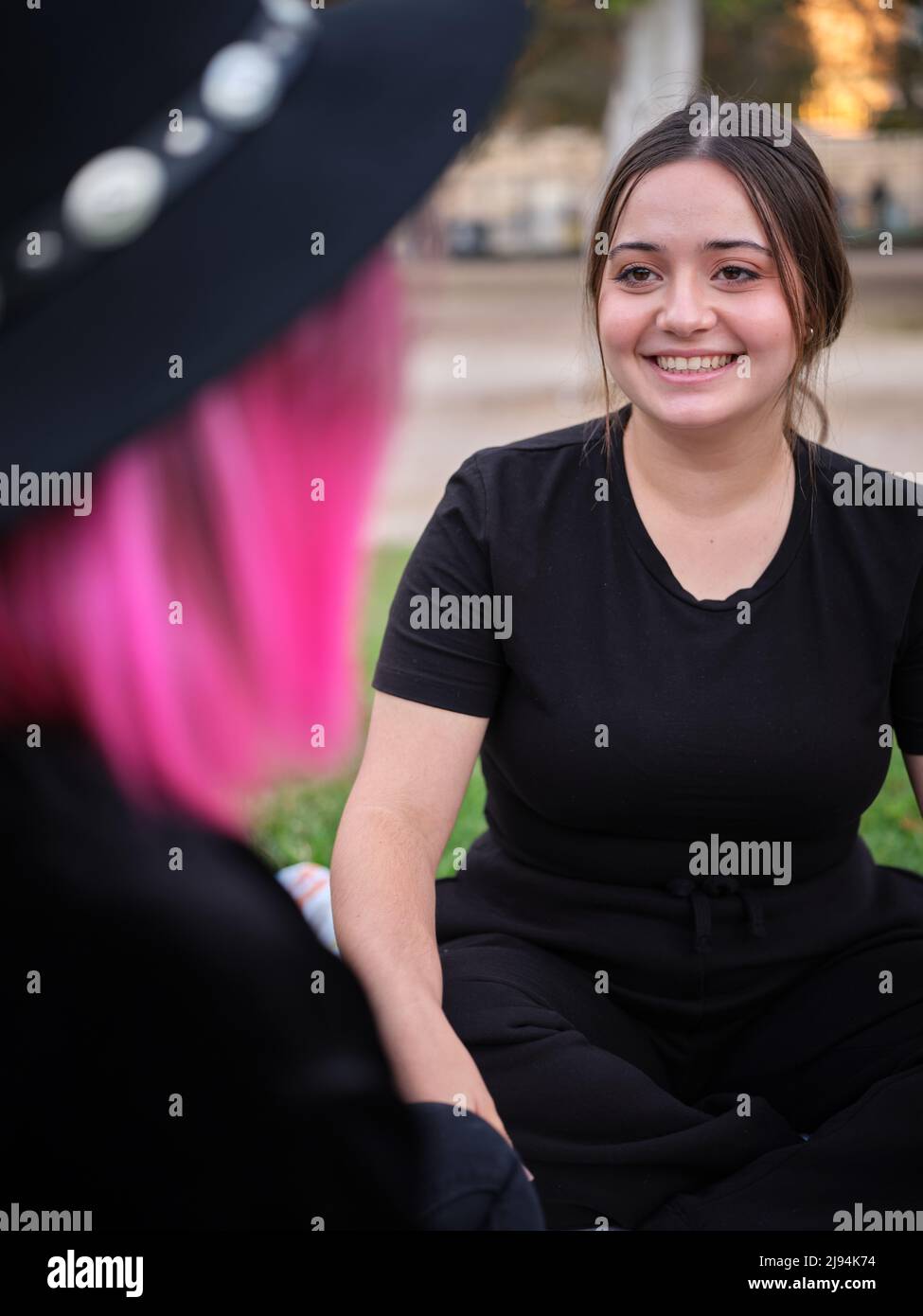 donna seduta sorridendo e guardando la sua amica Foto Stock