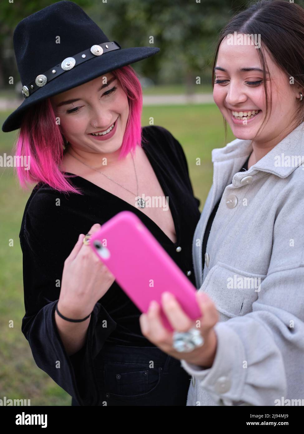 due giovani donne che scattano foto di se stessi con il telefono mentre ride Foto Stock