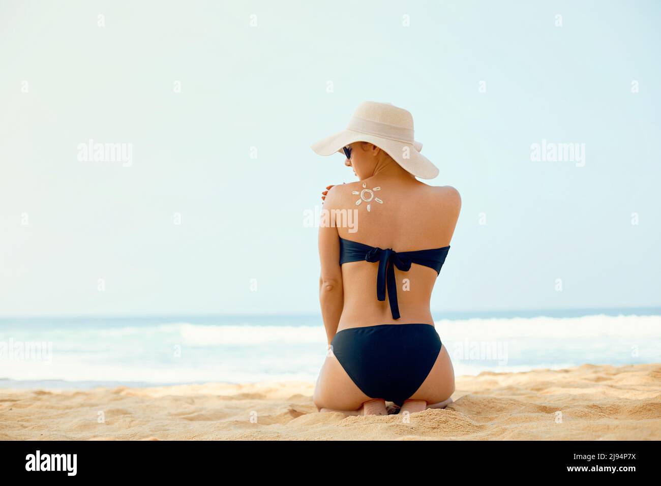 Bella Donna in Bikini applicazione crema solare sulla schiena abbronzata.  Protezione solare. Cura della pelle e