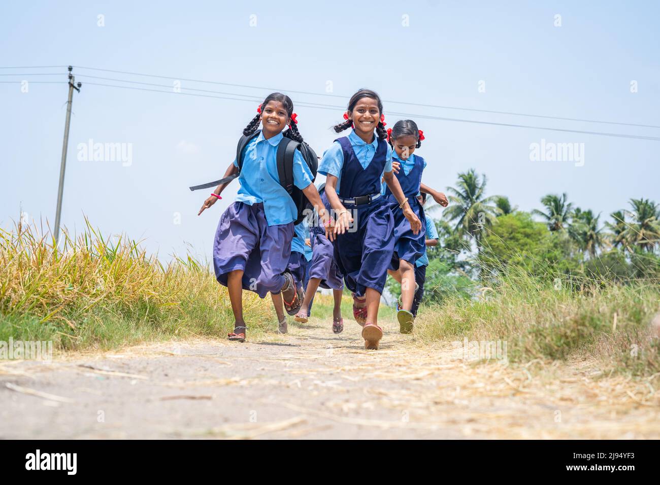 gruppo di ragazze scolastiche che corrono a casa in gara dopo la scuola vicino a terra di fattoria al villaggio - concetto di eccitato, allegro ed energico Foto Stock