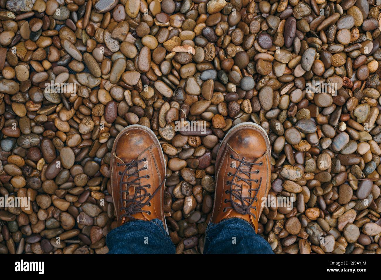 Gli stivali da uomo si trovano su una lussureggiante passerella in pietra naturale Foto Stock