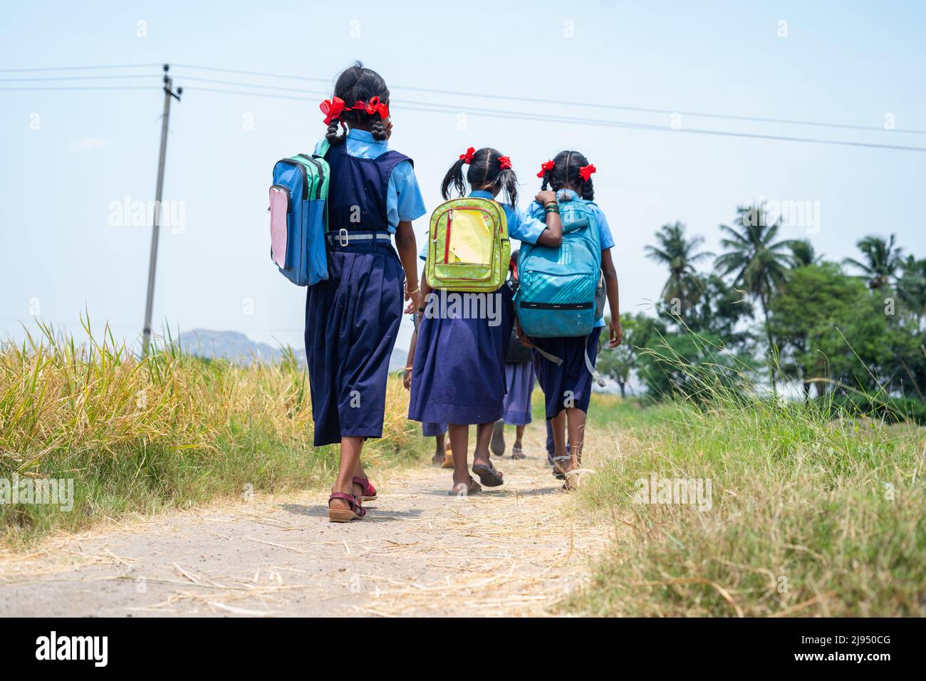Back view shot di villaggio bambini in uniforme andare a casa da scuola dopo classe - concetto di istruzione, stile di vita infantile e amicizia Foto Stock
