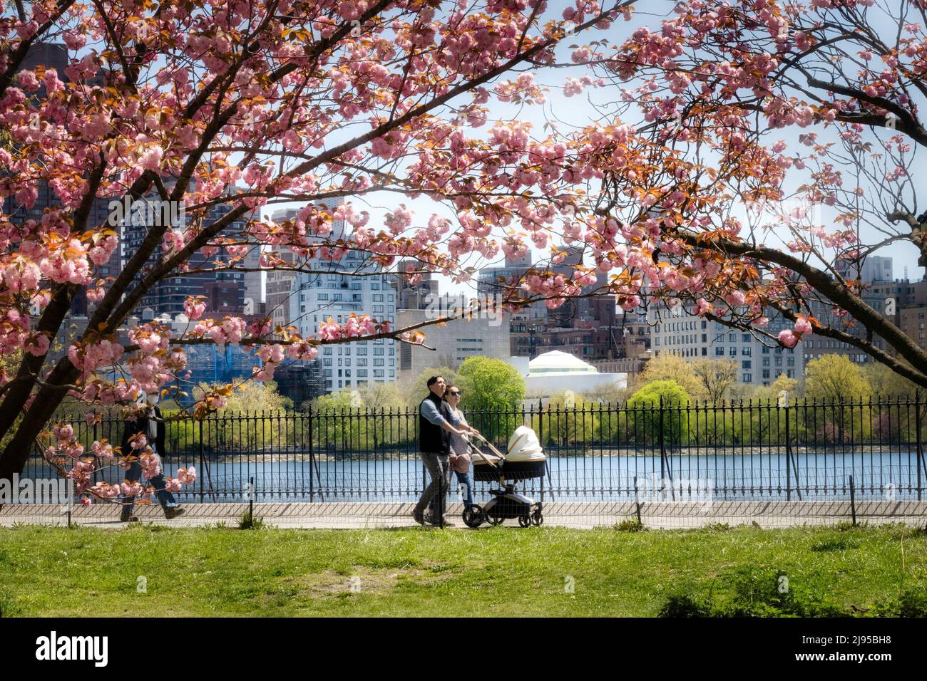 Una giovane coppia si gode una giornata di primavera nel pomeriggio con il proprio bambino a Central Park vicino al serbatoio, New York City, USA 2022 Foto Stock