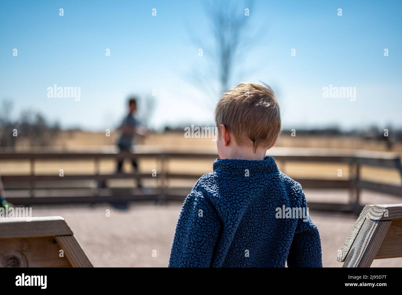 Bambino in attesa lungo la recinzione per il prossimo round di gaga ball in un parco giochi della scuola. Foto Stock