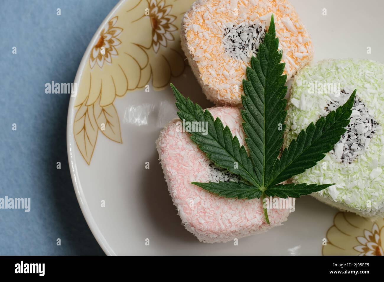 Dessert di cannabis. Delizia turca con fiocchi di cocco su un piatto, vista dall'alto. Foglia di marijuana verde. Composizione di cibo di canapa con olio CBD. Foto Stock
