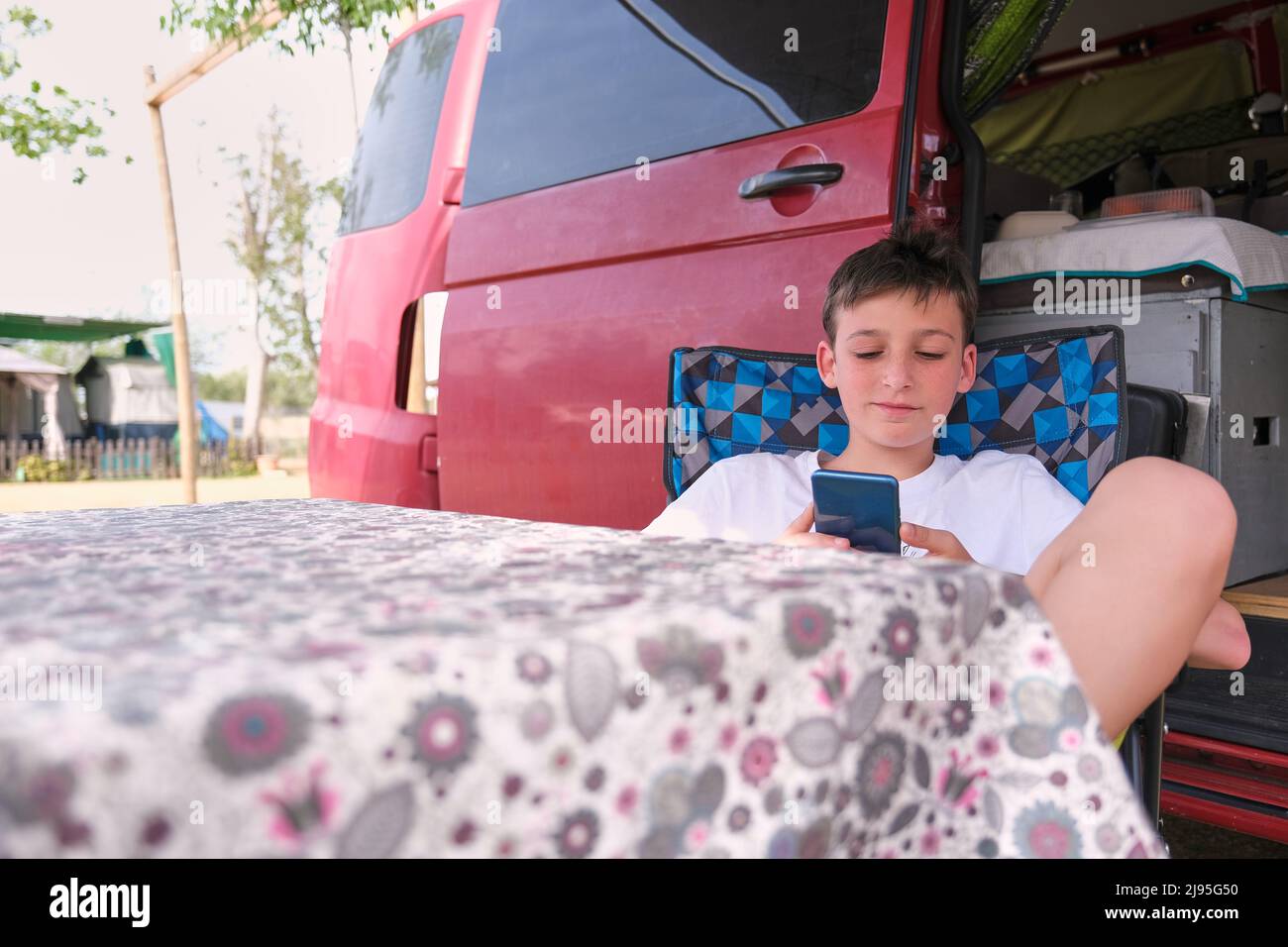 Ragazzo con cellulare rilassante fuori RV Foto Stock