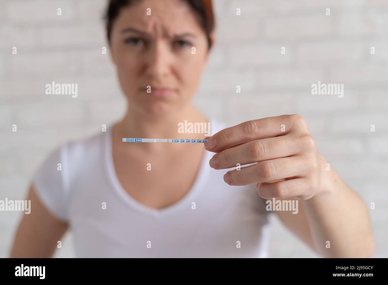 La donna infelice mostra un rapido test negativo per l'ovulazione. Il concetto di violazione della funzione riproduttiva femminile. Ragazza frustrato. Luteinizzante Foto Stock