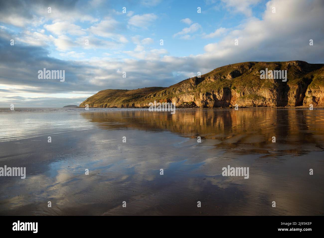 Brean Down si riflette nella sabbia bagnata di Brean Beach. Somerset, Regno Unito. Foto Stock