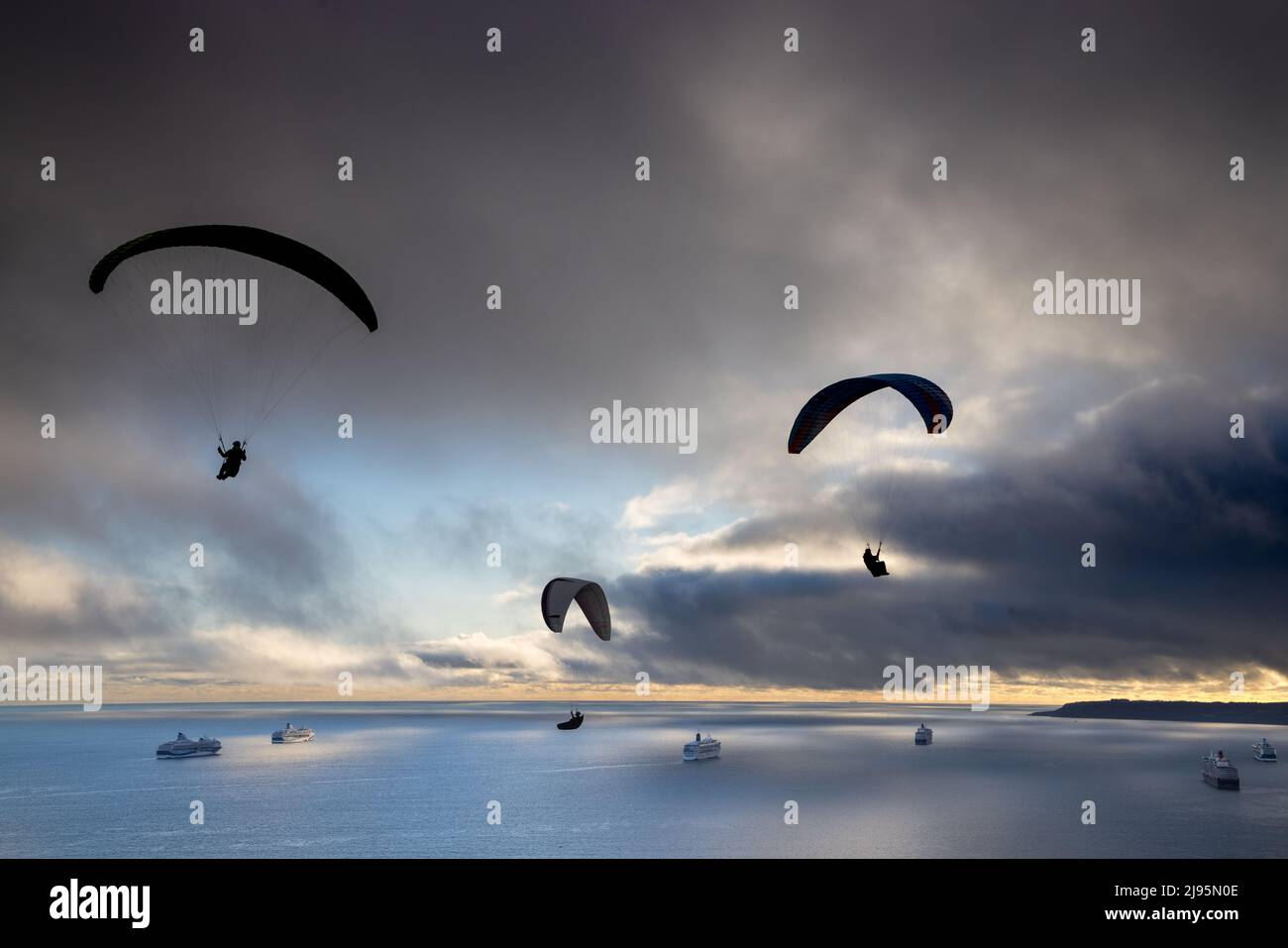 Parapendio che sorvolano le navi da crociera ancorate a Weymouth Bay, con Portland Beyond, Dorset, Inghilterra, Regno Unito Foto Stock