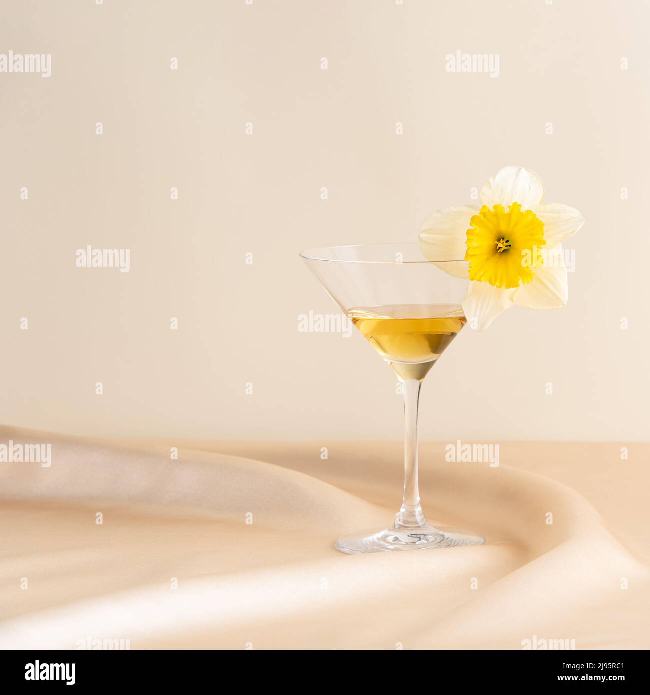 Bicchiere da cocktail con fiore, in raso ondulato rosa davanti a uno sfondo rosa. Concetto astratto minimo primavera ed estate. Layout isometrico. Squa Foto Stock