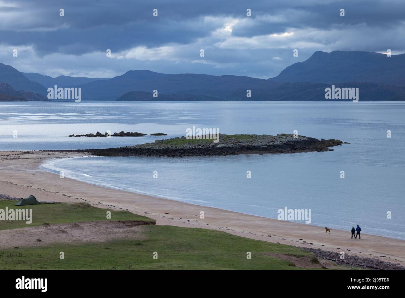 Mark e Rachel Littlejohn camminano il loro cane Red sulla spiaggia di Red Point all'alba, Loch Torridon, Wester Ross, Scozia, Regno Unito Foto Stock