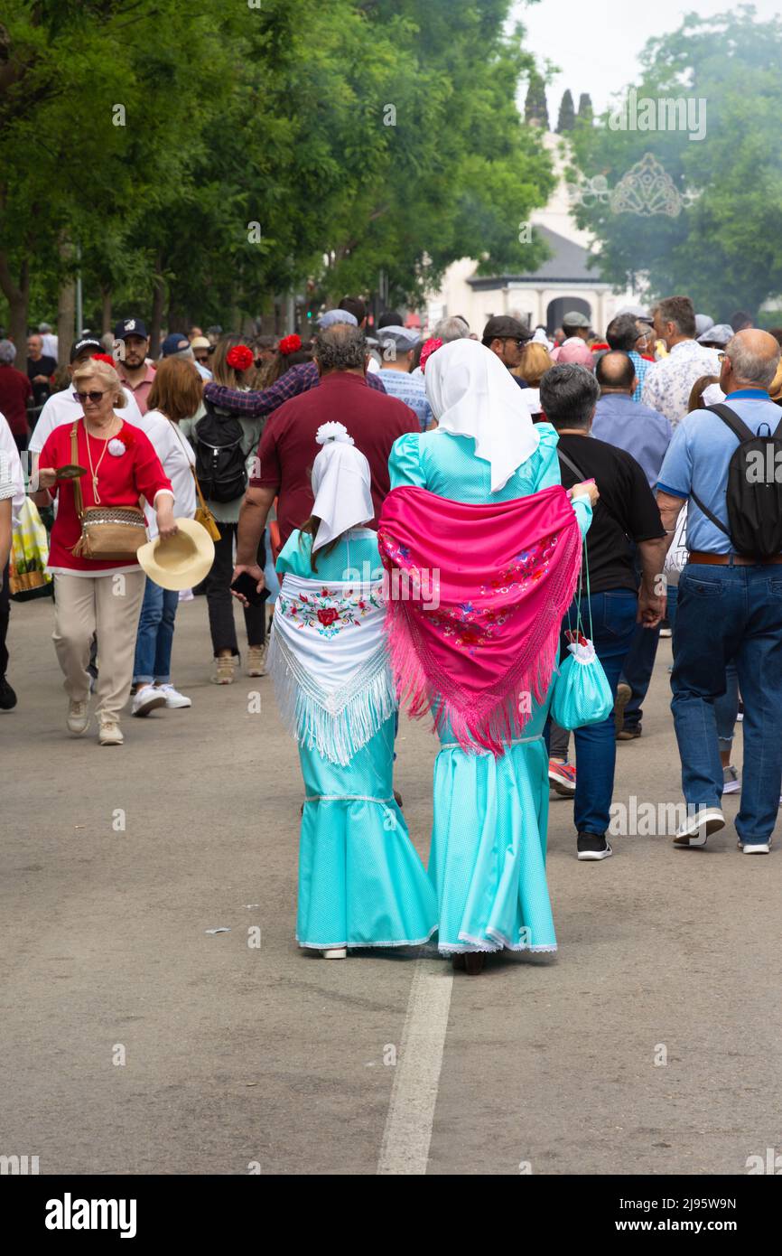 Madrid, Spagna; 15th maggio 2022: Un gruppo di persone in visita alle bancarelle della fiera di Sant'Isidro. Madre e figlia con le loro spalle si girarono vestite in t Foto Stock