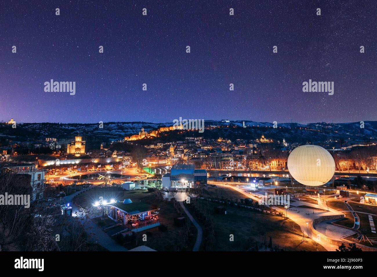 Tbilisi, Georgia. Cielo stellato cielo notturno sopra skyline città, vista panoramica del parco Rike a Tbilisi, Georgia. Chiesa di Metekhi, Fortezza di Narikala, Vecchio Foto Stock