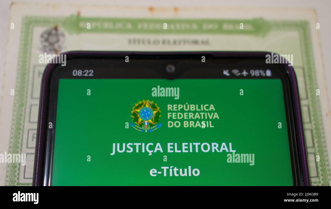 Tres Coroas, Brasile - Circa Maggio 2022: Scheda ID voter digitale brasiliano su uno schermo per smartphone, vecchia scheda id voter stampata sullo sfondo - personale d Foto Stock