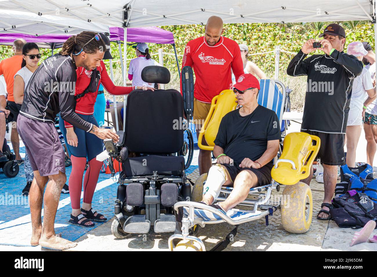Miami Beach Florida, Sabrina Cohen Adaptive Beach Day, disabili bisogni speciali disabili waterwheels galleggianti sedia a rotelle, uomo nero volontario maschile Foto Stock