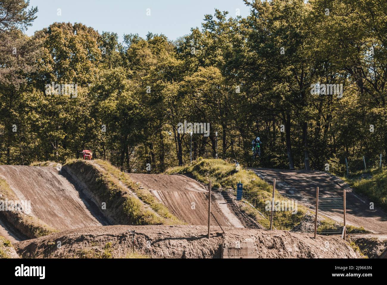 Vista ad angolo elevato di una pista da motocross. Sul lato destro della pista un motociclista salta. Spazio di copia. Concetto di motocross, sport estremi. Foto Stock