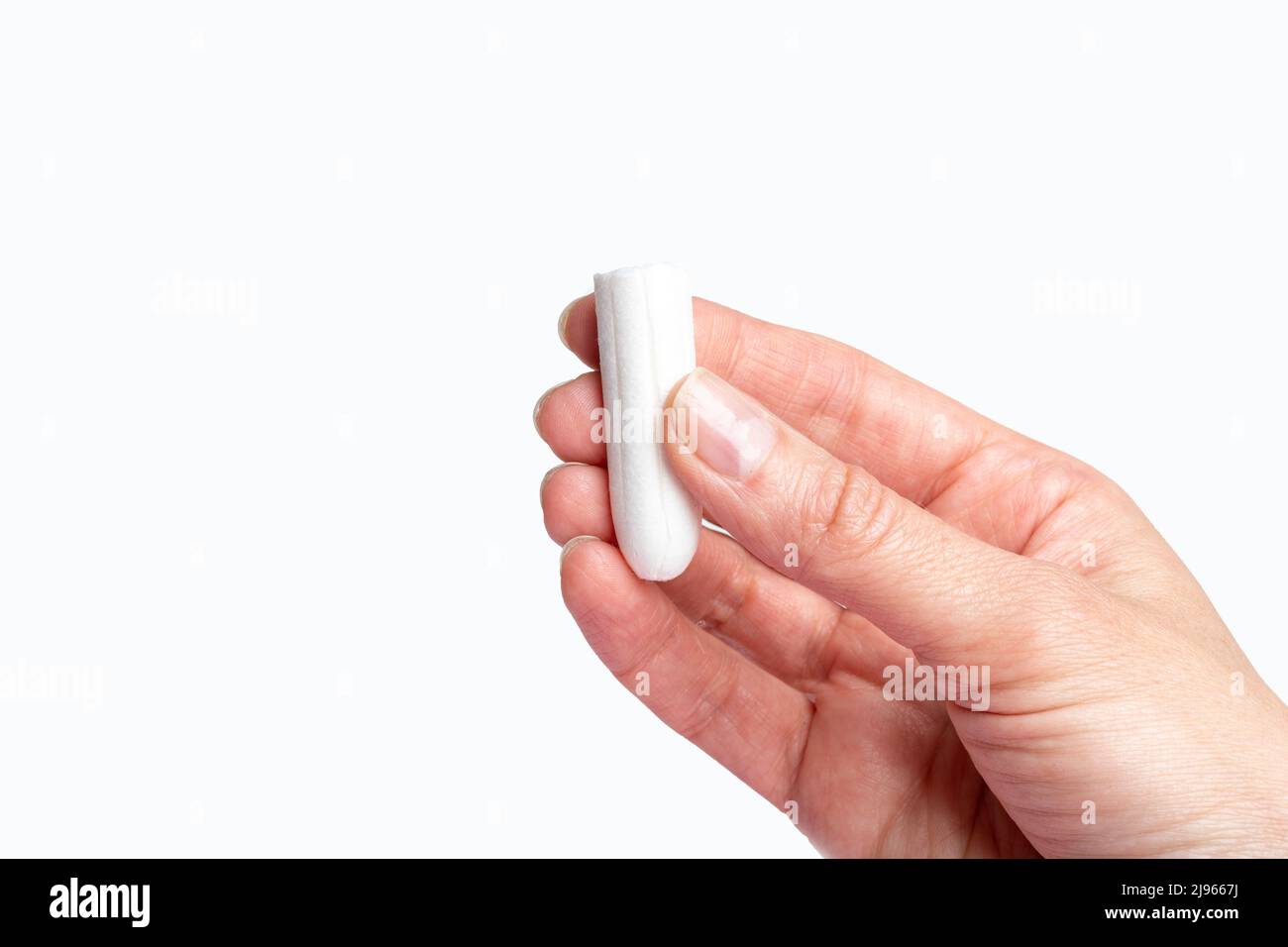 Una mano che tiene un tampone di cotone bianco su sfondo bianco. Il concetto del ciclo mestruale. Igiene e salute delle donne. Salute delle donne concep Foto Stock