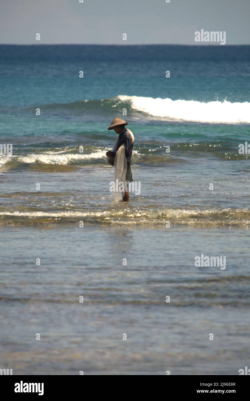 Un pescatore che prepara la rete da pesca per pescare sulle acque costiere della spiaggia di Tanjung Setia a Krui, Pesisir Barat, Lampung, Indonesia. Foto Stock