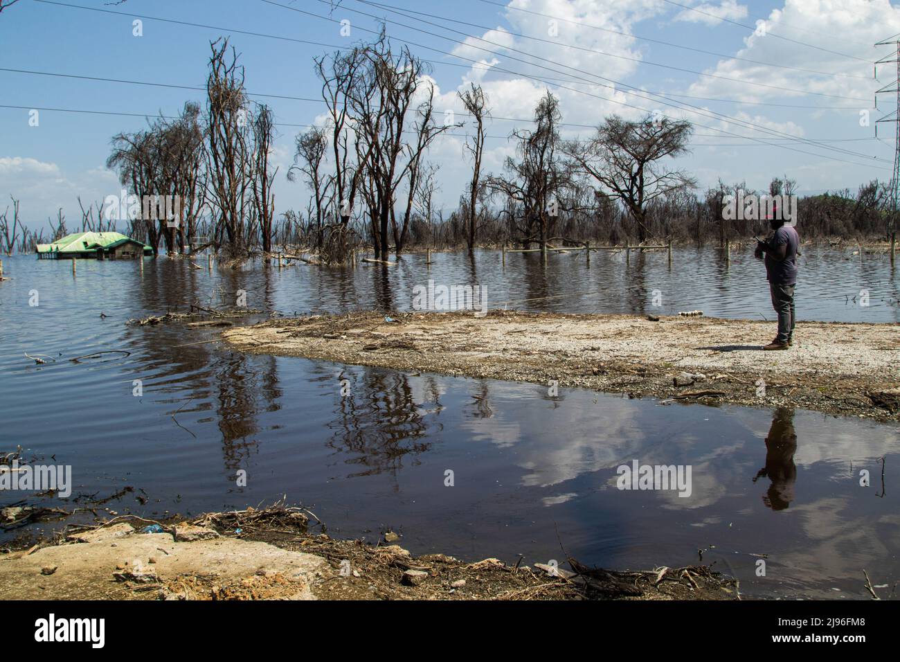 Un uomo visto in piedi sulla riva del lago ora inondato Nakuru. Negli ultimi 10 anni, i laghi della Rift Valley sono cresciuti costantemente in quello che gli esperti indicano come gli effetti del cambiamento climatico. Le alluvioni hanno sfollato centinaia di persone dalle loro case e dal loro lavoro, le comunità povere ed emarginate ne hanno il peso maggiore. Foto Stock