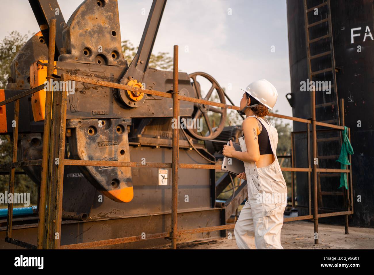 Ingegneria petrolchimica asiatica donna con casco di sicurezza in piedi nella struttura petrolifera industria petrolchimica. Foto Stock