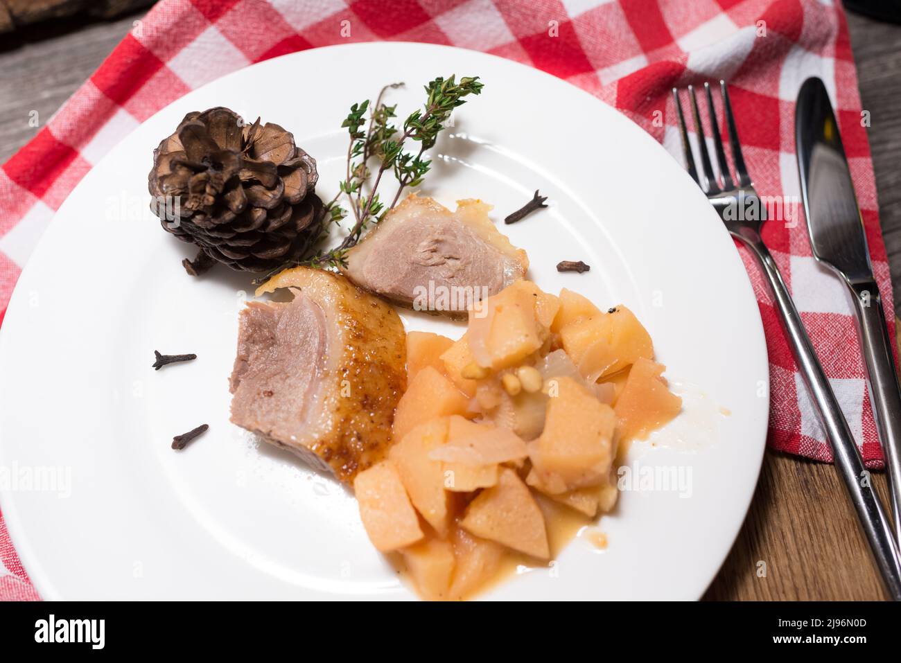 Anatra con pera caramellata e pinoli. Tovagliolo a scacchi. Posate. Foto Stock