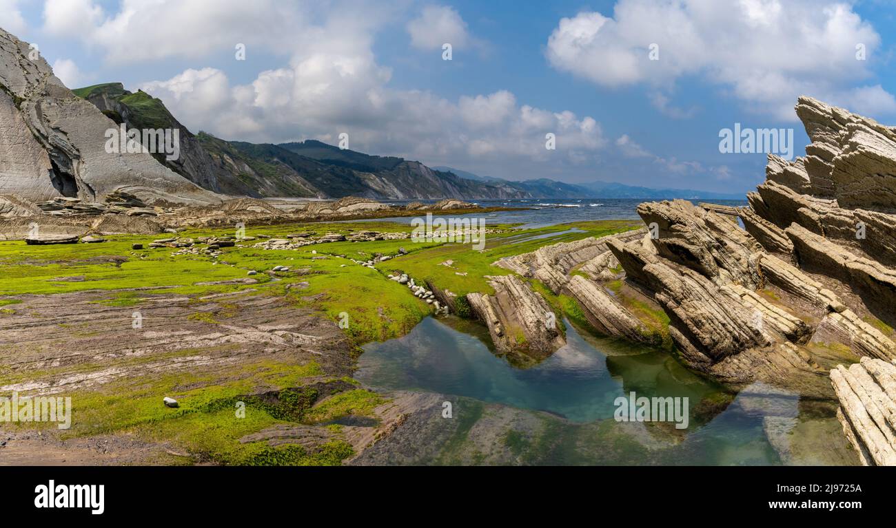 Una vista panoramica delle formazioni rocciose di Flysch e delle scogliere con piscine di marea sulla costa dei Paesi Baschi vicino a Zumaia Foto Stock