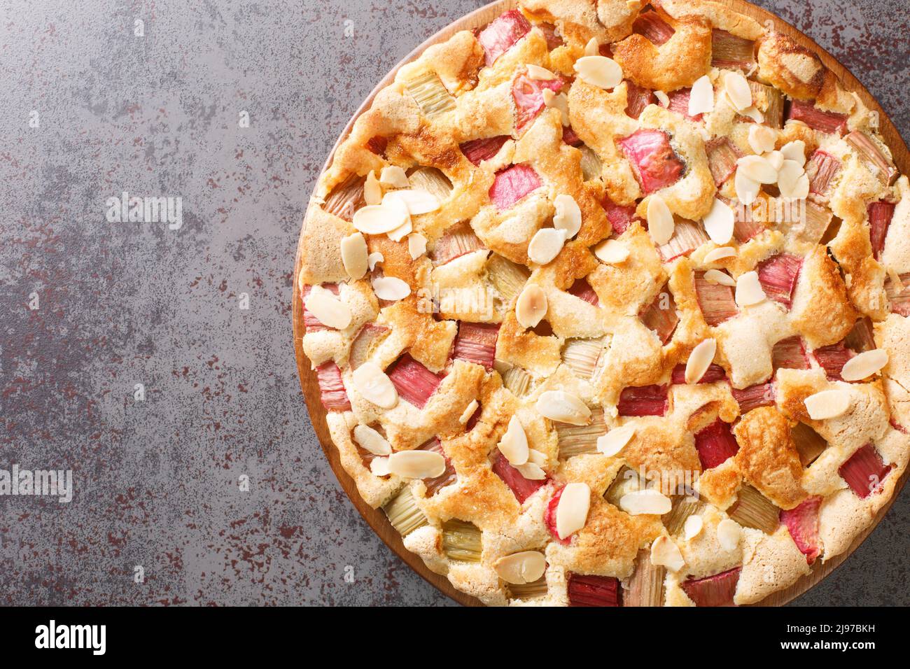 Torta scandinava Rhubarb con scaglie di mandorle primo piano nel piatto sul tavolo. Vista dall'alto orizzontale Foto Stock