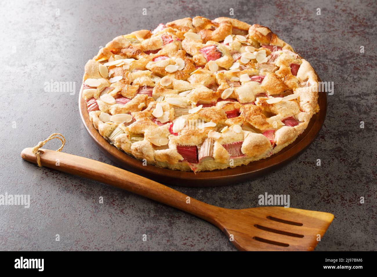 Torta tradizionale di rabarbaro fresco con le mandorle in primo piano in un piatto sul tavolo. Orizzontale Foto Stock