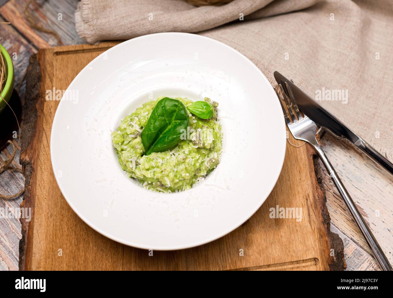 Piatto di risotto verde con foglie di basilico e formaggio. Cibo sano. Tenero arborio aromatizzato con spinaci verdi e infuso con carne di agnello brot Foto Stock