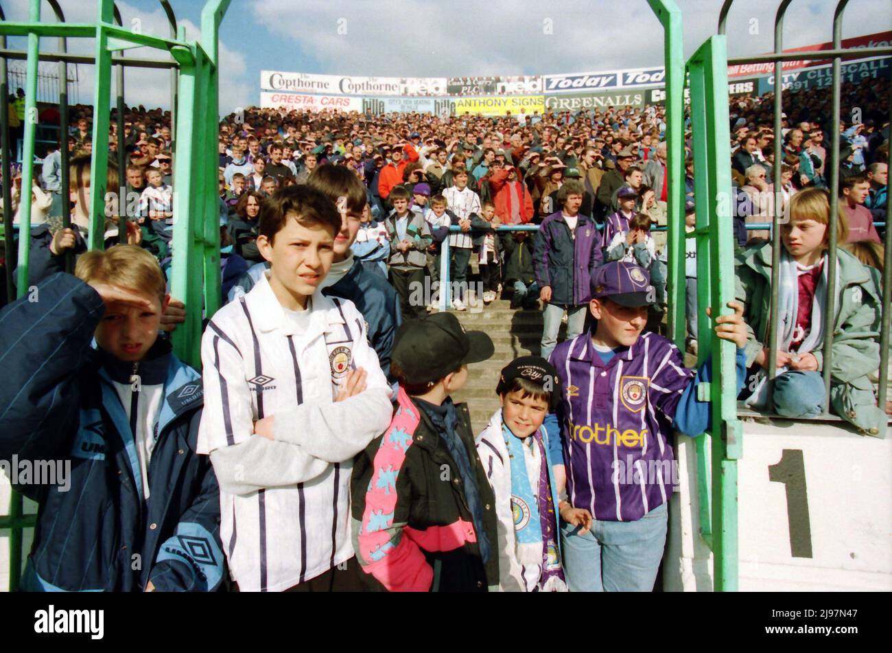I fan si levano in piedi sulle terrazze dietro la scherma sul Kippax a Maine Road. Per la partita Manchester City contro Norwich City, 16 aprile 1994. Le recenti invasioni di campo potrebbero costringere le autorità a pensare ai metodi di prevenzione, ma sarebbe altamente improbabile che vedessimo i tifosi di calcio dietro le recinzioni. Foto Stock
