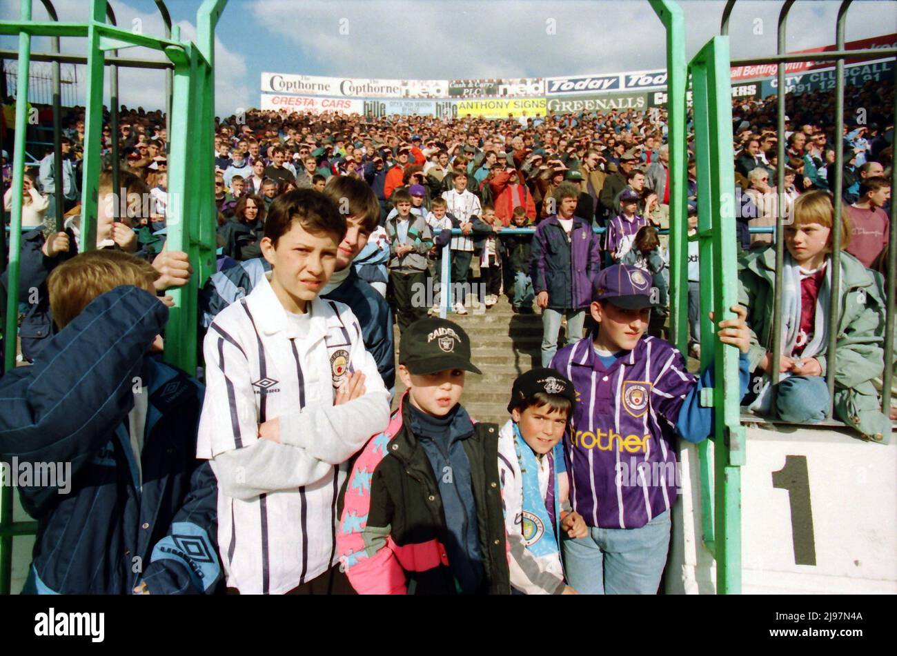 I fan si levano in piedi sulle terrazze dietro la scherma sul Kippax a Maine Road. Per la partita Manchester City contro Norwich City, 16 aprile 1994. Le recenti invasioni di campo potrebbero costringere le autorità a pensare ai metodi di prevenzione, ma sarebbe altamente improbabile che vedessimo i tifosi di calcio dietro le recinzioni. Foto Stock