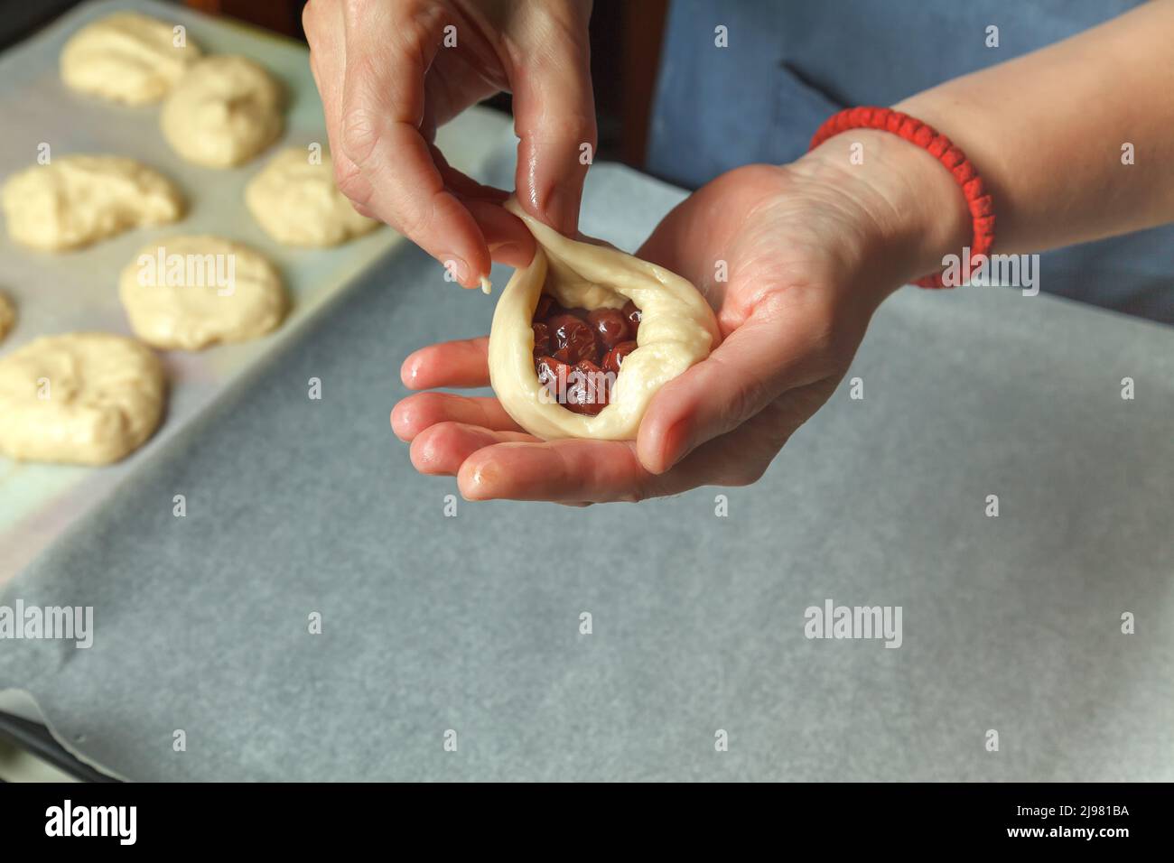 Lo chef pasticceria mette un cucchiaio di ciliegia nella pasta per pane preparata Foto Stock