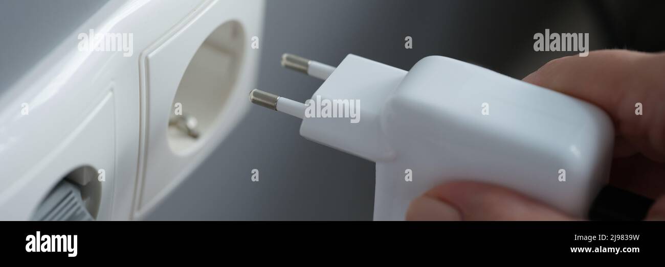 Collegare il caricabatterie a una presa a muro, in primo piano Foto Stock