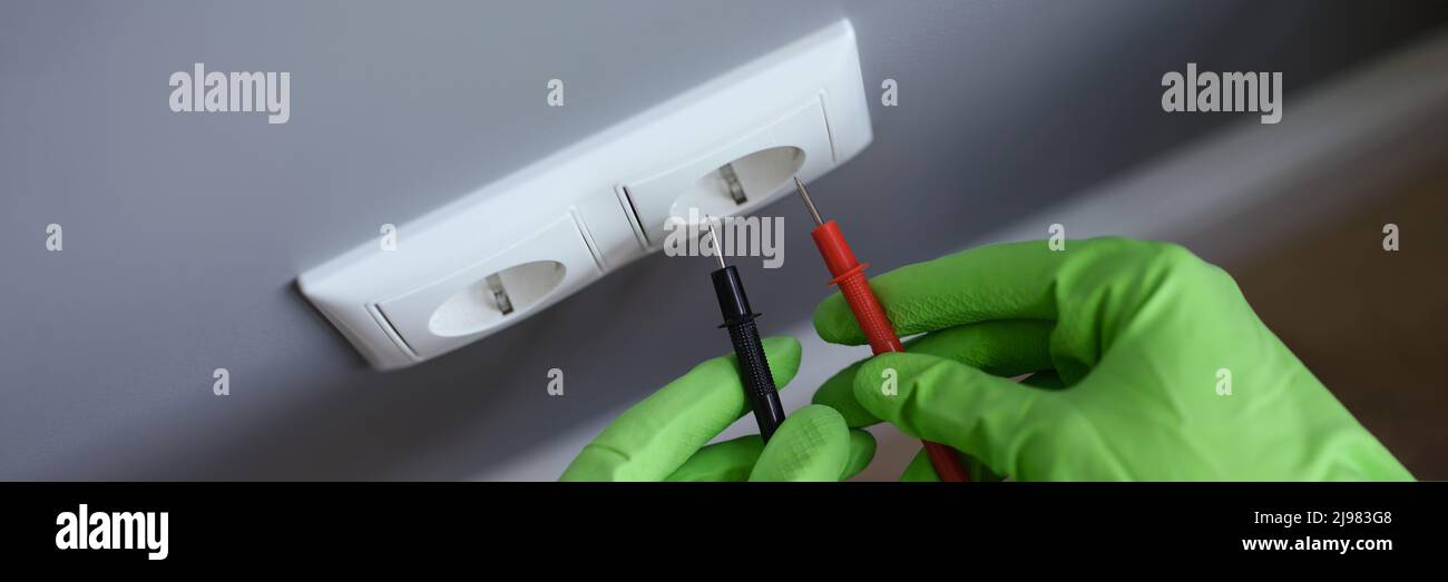 I guanti con le mani misurano la tensione nella presa con un attrezzo Foto Stock
