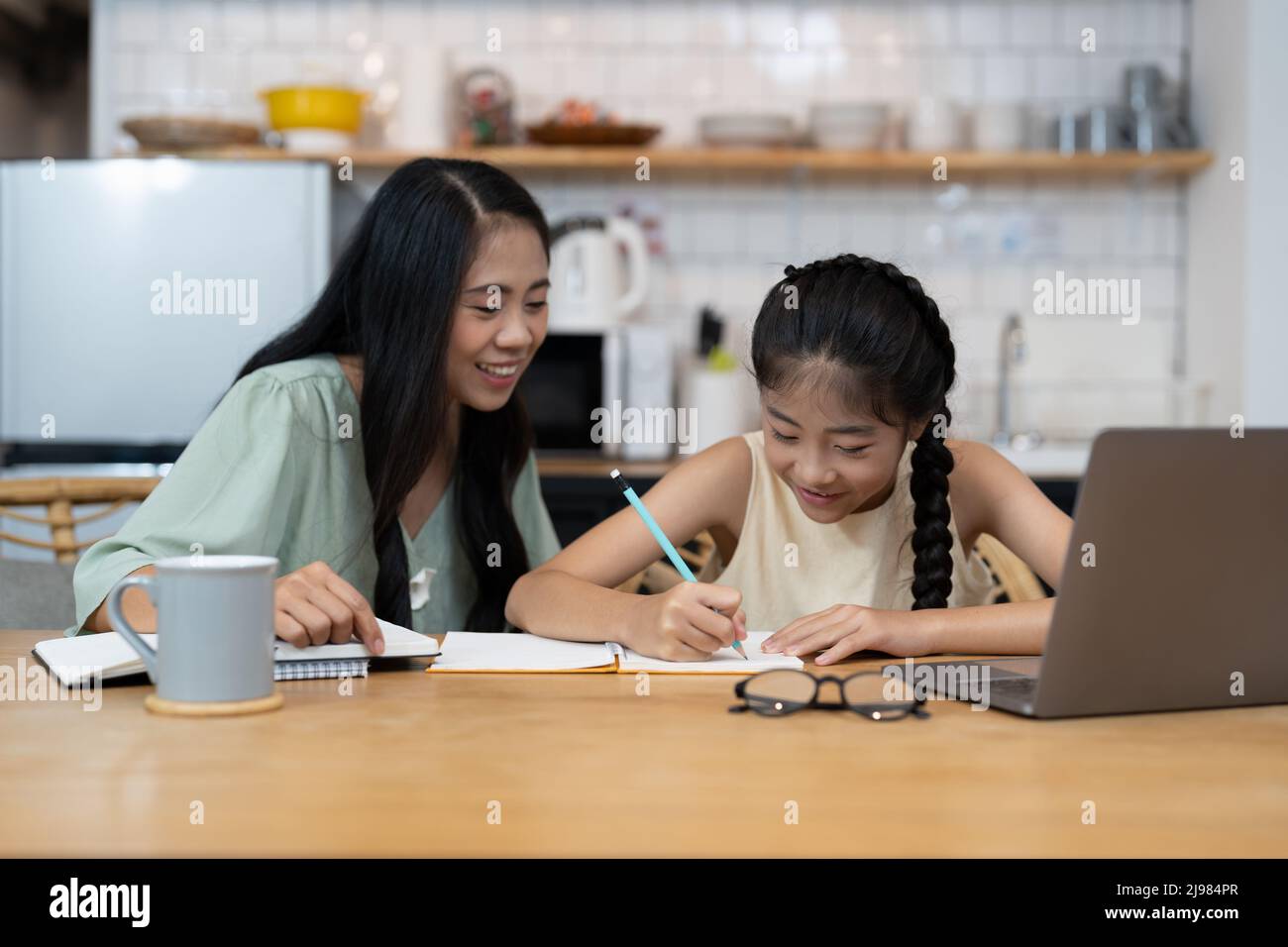 Madre e bambino asiatico bambina imparando su computer portatile facendo i compiti studiare la conoscenza con il sistema di e-learning di formazione in linea. Bambini Foto Stock