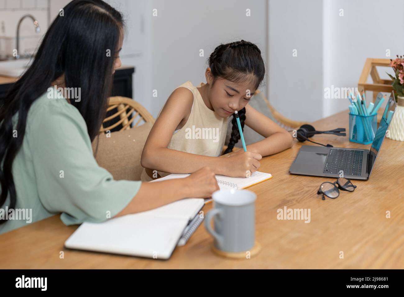 Madre e bambino asiatico ragazza in linea imparando sul computer portatile che fa i compiti studiare la conoscenza con il sistema di e-learning di formazione in linea Foto Stock