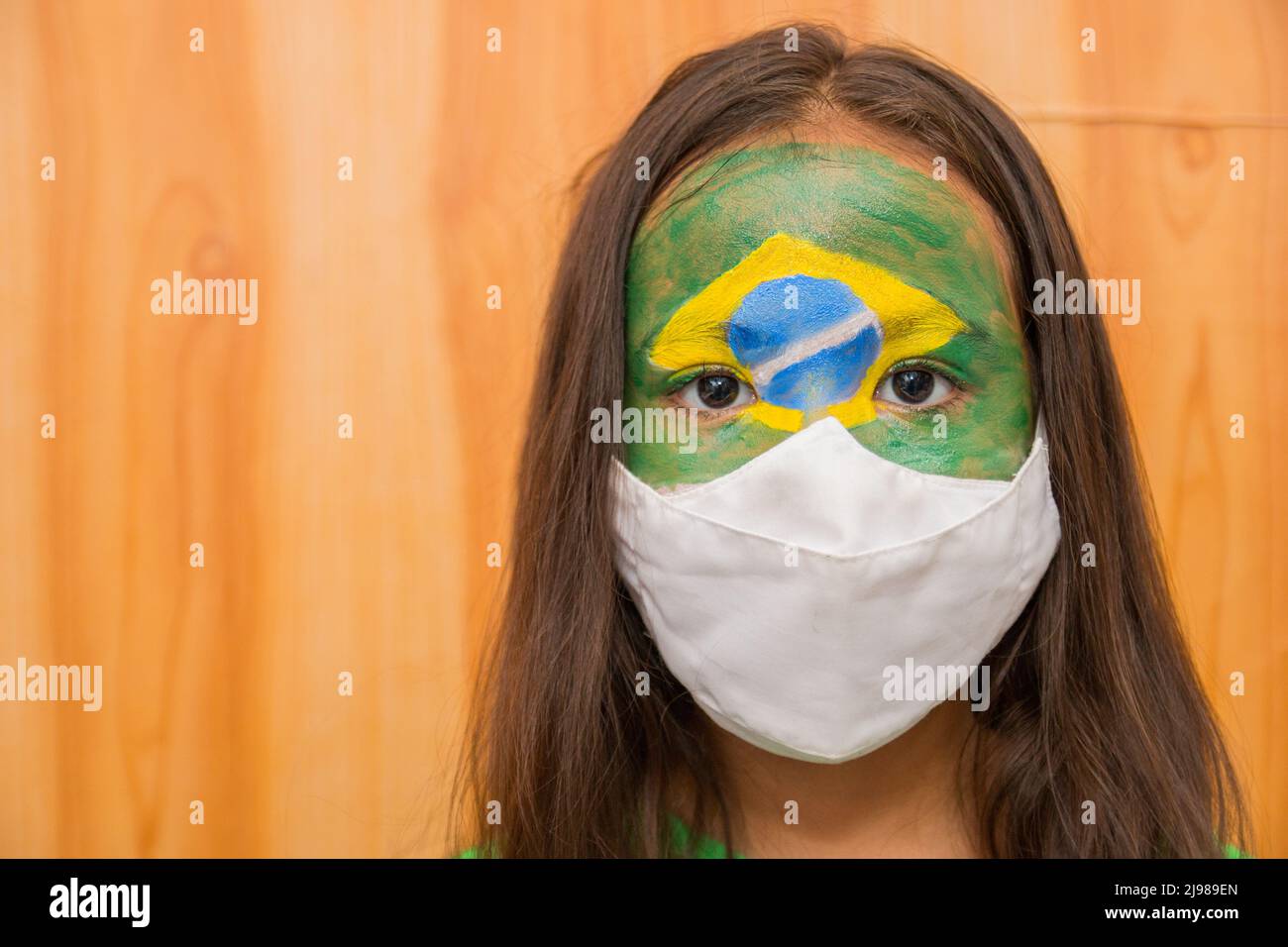 Bambino con una maschera con il suo volto dipinto con la bandiera del Brasile. Foto Stock