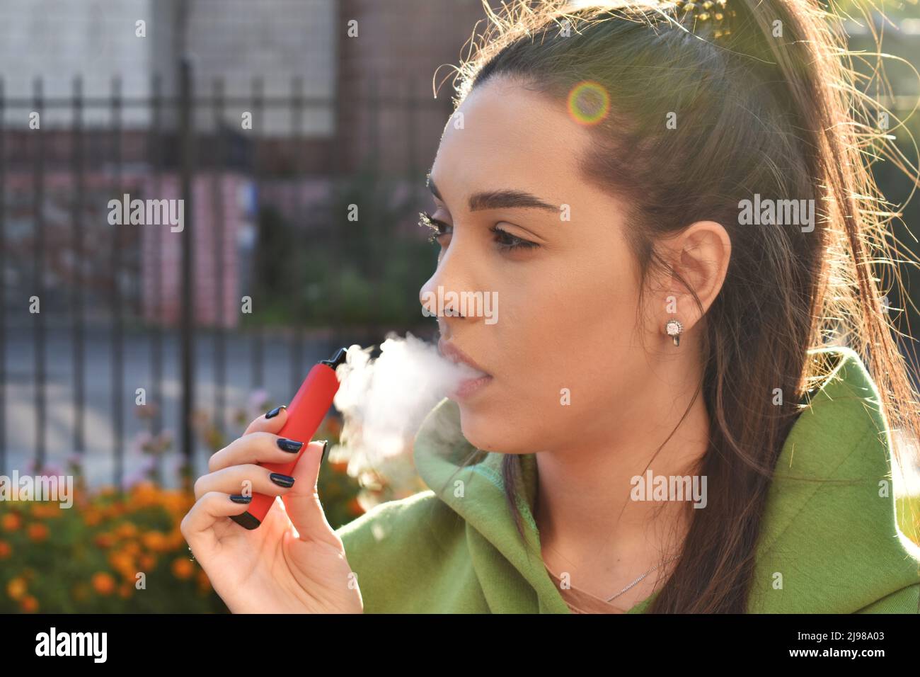 Bella bruna fumo di sigaretta elettronica in luoghi pubblici Foto Stock