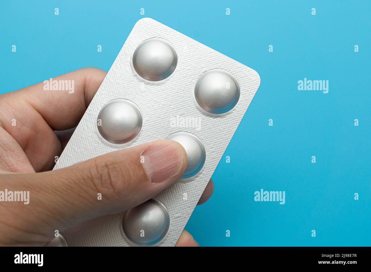 Pillole confezionate singolarmente su sfondo blu Foto Stock