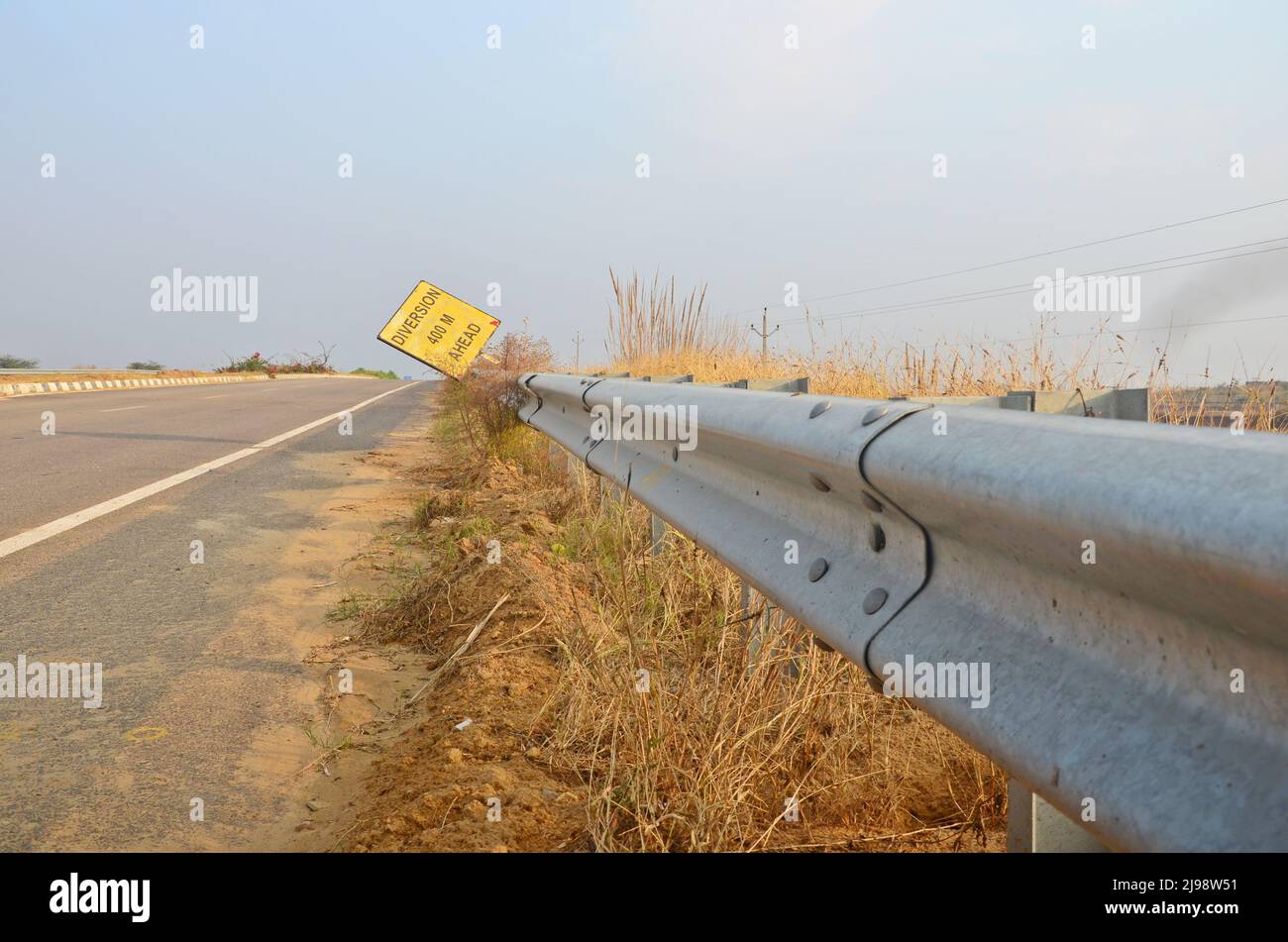 Un cartello stradale vicino a un'autostrada con barriera di sicurezza in acciaio inox. Foto Stock