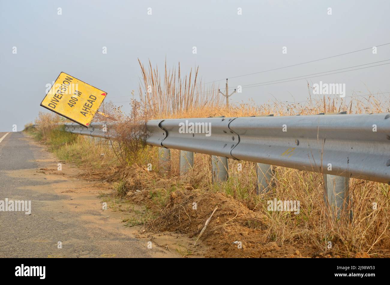 Un cartello stradale vicino a un'autostrada con barriera di sicurezza in acciaio inox. Foto Stock