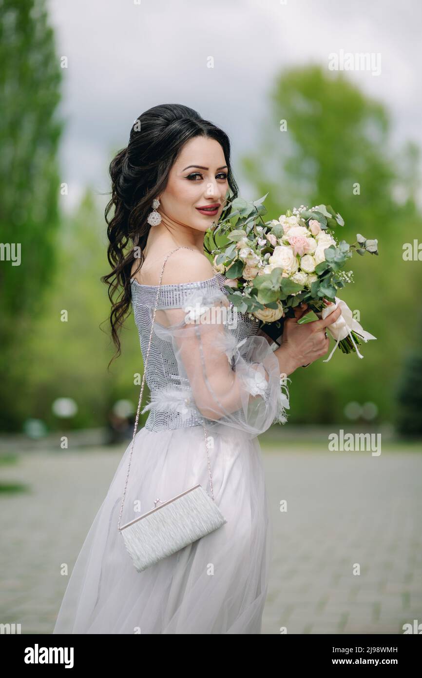 Scatto medio di bridesmaid sorridente con bouquet nuziale e vestito alla moda ed elegante. Foto della sirena Foto Stock