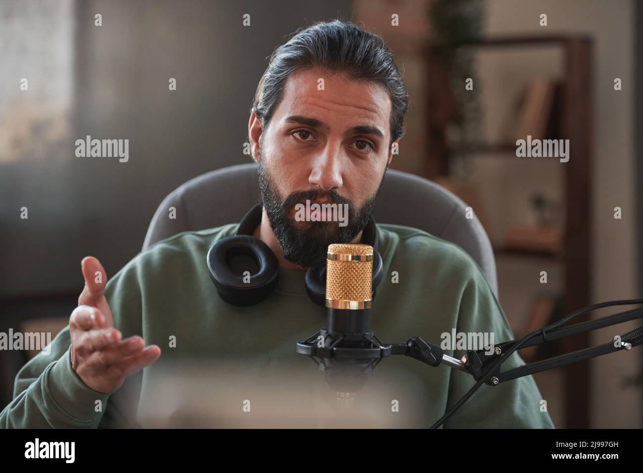 Medio ritratto di primo piano del giovane influencer mediorientale che crea contenuti per blog parlando con la fotocamera Foto Stock