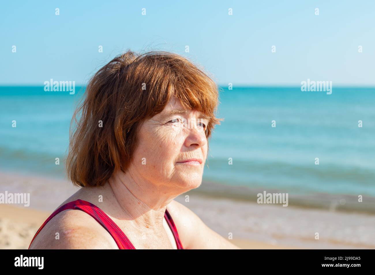 la donna anziana guarda via alla costa marina. Vacanze di pensionamento in un giorno d'estate. Foto Stock